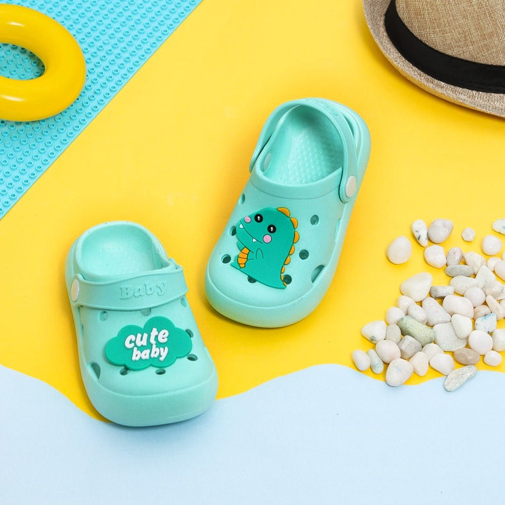Aqua blue toddler clogs with cute dinosaur motif on a colorful background