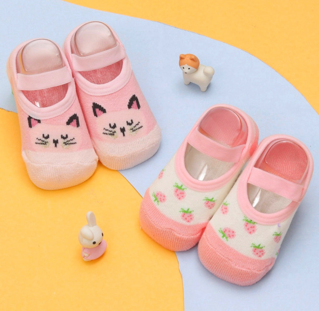 Image of pink kitty print cotton-leather socks for baby girls by Yellow Bee, top view on a yellow and blue background.