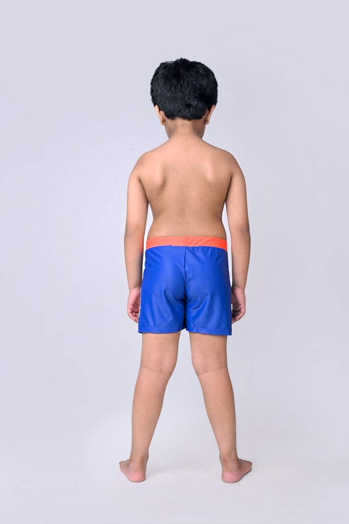 Back view of boy in blue swim shorts with a bright red waistband, showcasing a snorkeling shark design