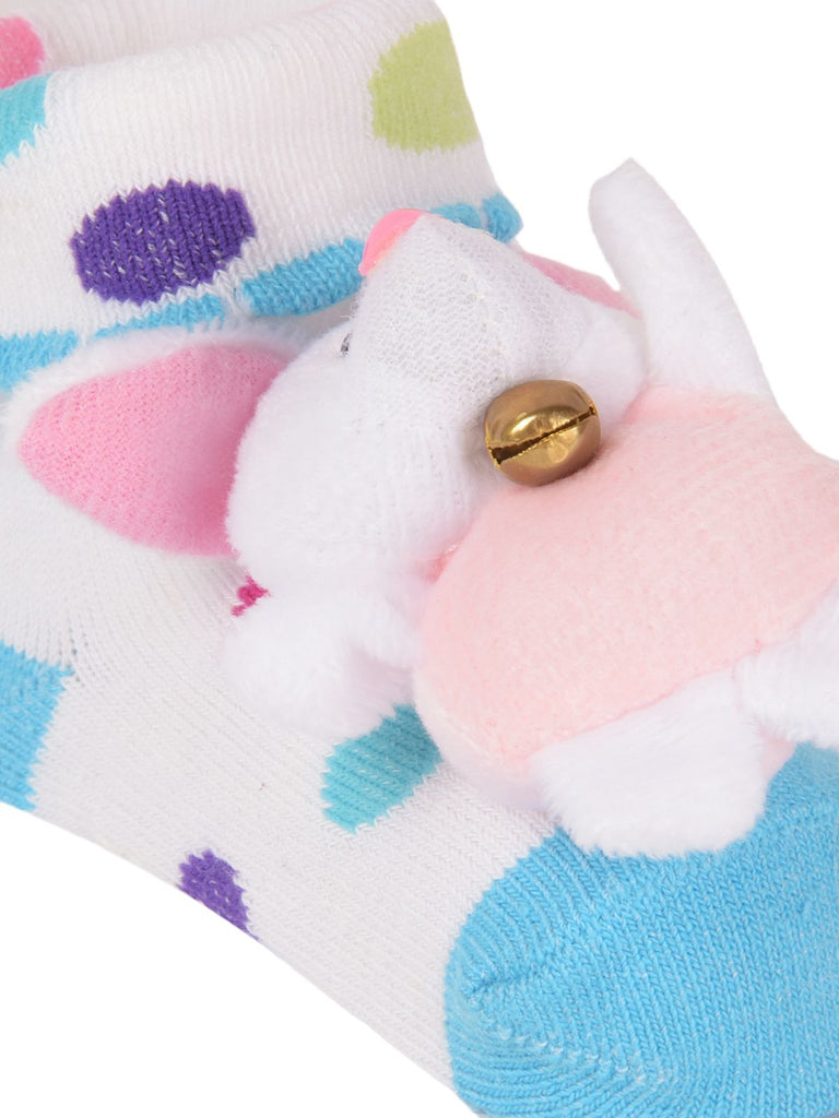 Close-up of infant socks with a cute bunny stuffed toy and gold bell detail.