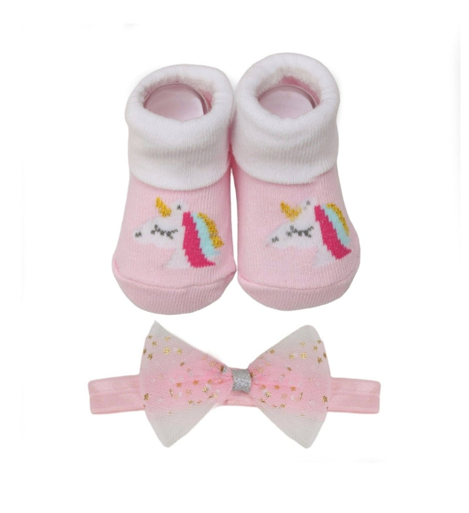 Baby's pink unicorn socks and matching bow headband set on a yellow background.