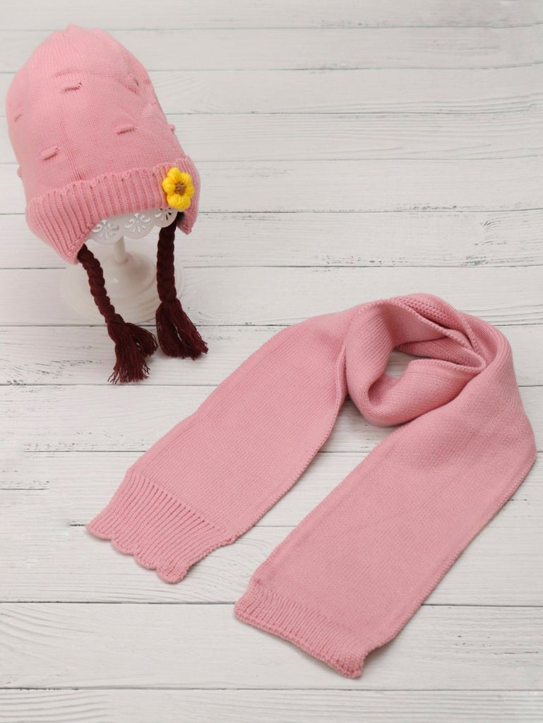 Pink knitted beanie with eye applique and pom-pom for boys on display stand.