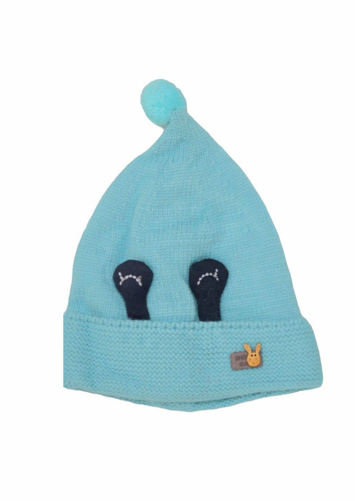 Close-up of a boy's light blue beanie hat with a cute eye design and soft pom-pom on top