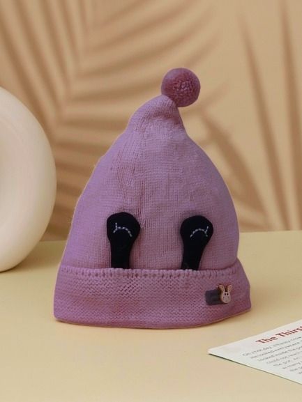 Mauve winter beanie hat with playful eye applique and a pom-pom for toddler girls.