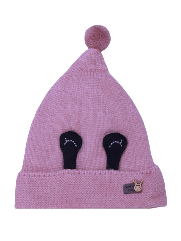 Front view of a girls' mauve beanie with eye details and a soft pom-pom on top.