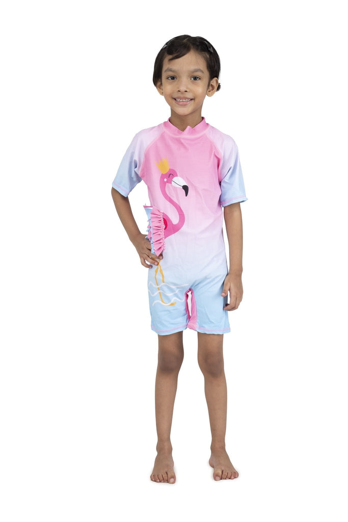 Front view of a girl smiling in Yellow Bee's flamingo swimsuit with half sleeves and ruffle details.