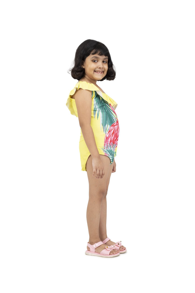 Side view of girl in a yellow ruffle-sleeve swimsuit with flamingo design by Yellow Bee.