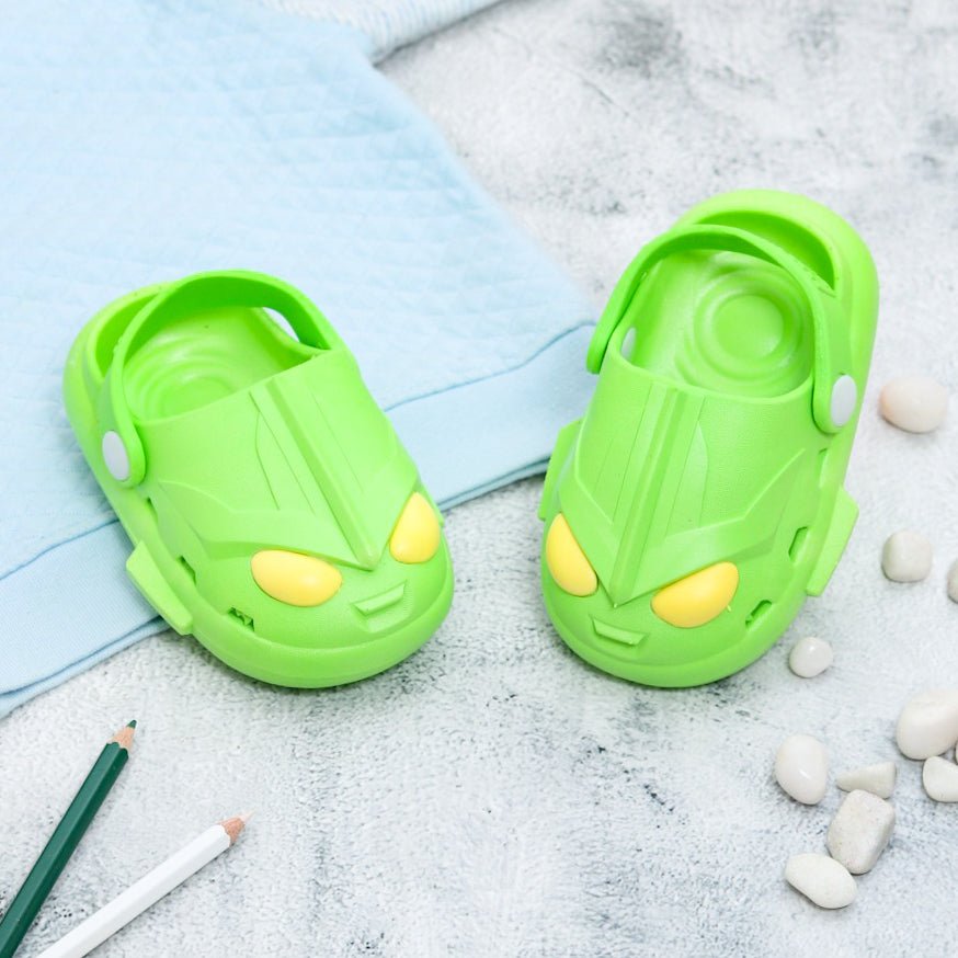 Pair of Green Alien Clogs for kids with fun intergalactic design on a soft background.