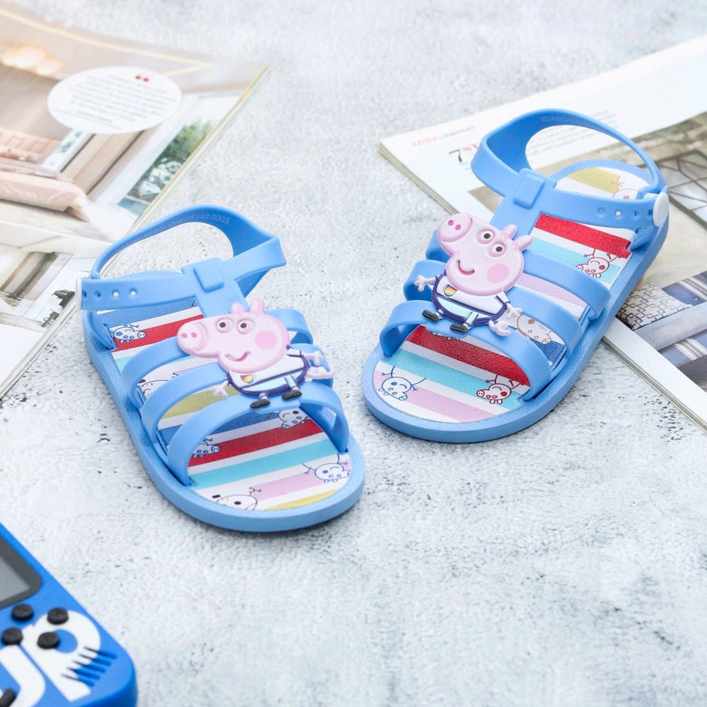 Bright and colorful George by Yellow Bee character patterned children's sandals on a magazine background.