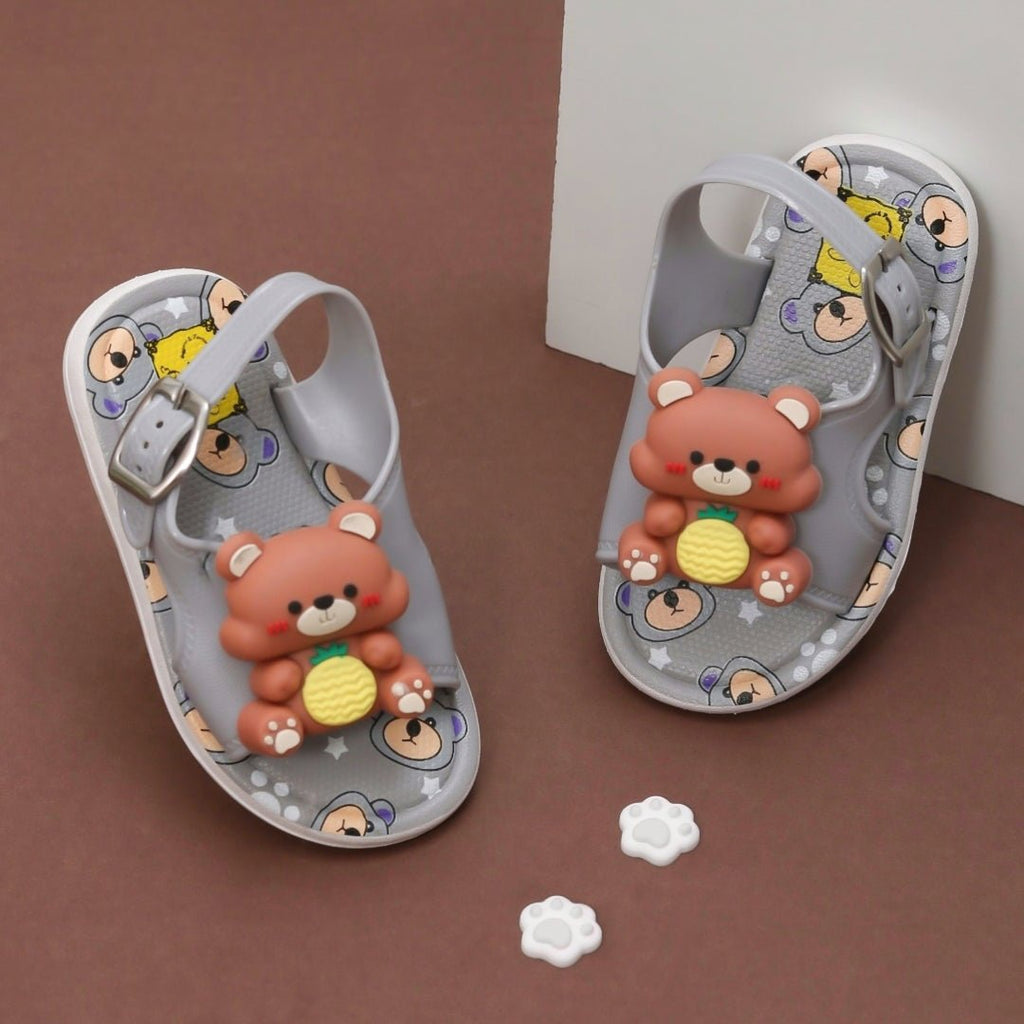 Pair of Grey Teddy Applique Sandals with playful teddy bear figures on a brown background.