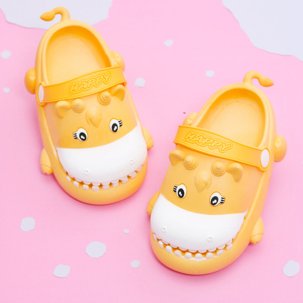 Bright yellow toddler clogs with a cheerful hippo face pattern on a pink polka-dotted background.