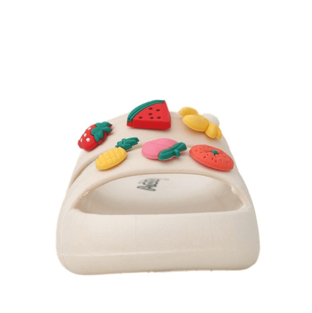 Close-up of the colorful fruit decorations on the slide sandal against a cream strap