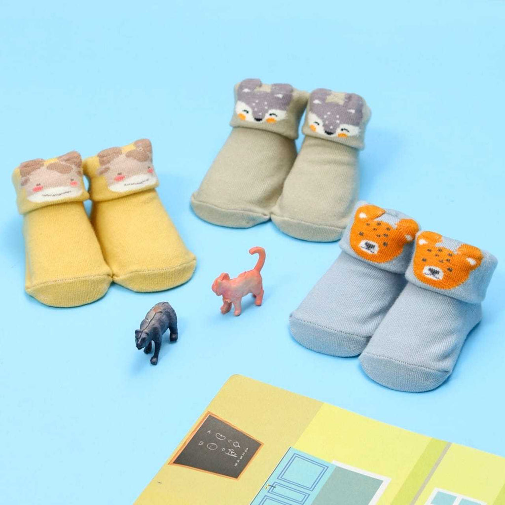 Baby boy's giraffe and puppy socks set displayed with tropical leaves and toy animals.
