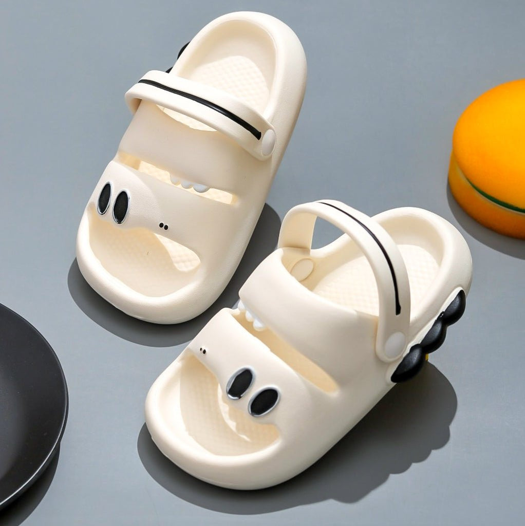  Pair of white dino-themed sandals with black scales accent, perfect for kids' outdoor play.