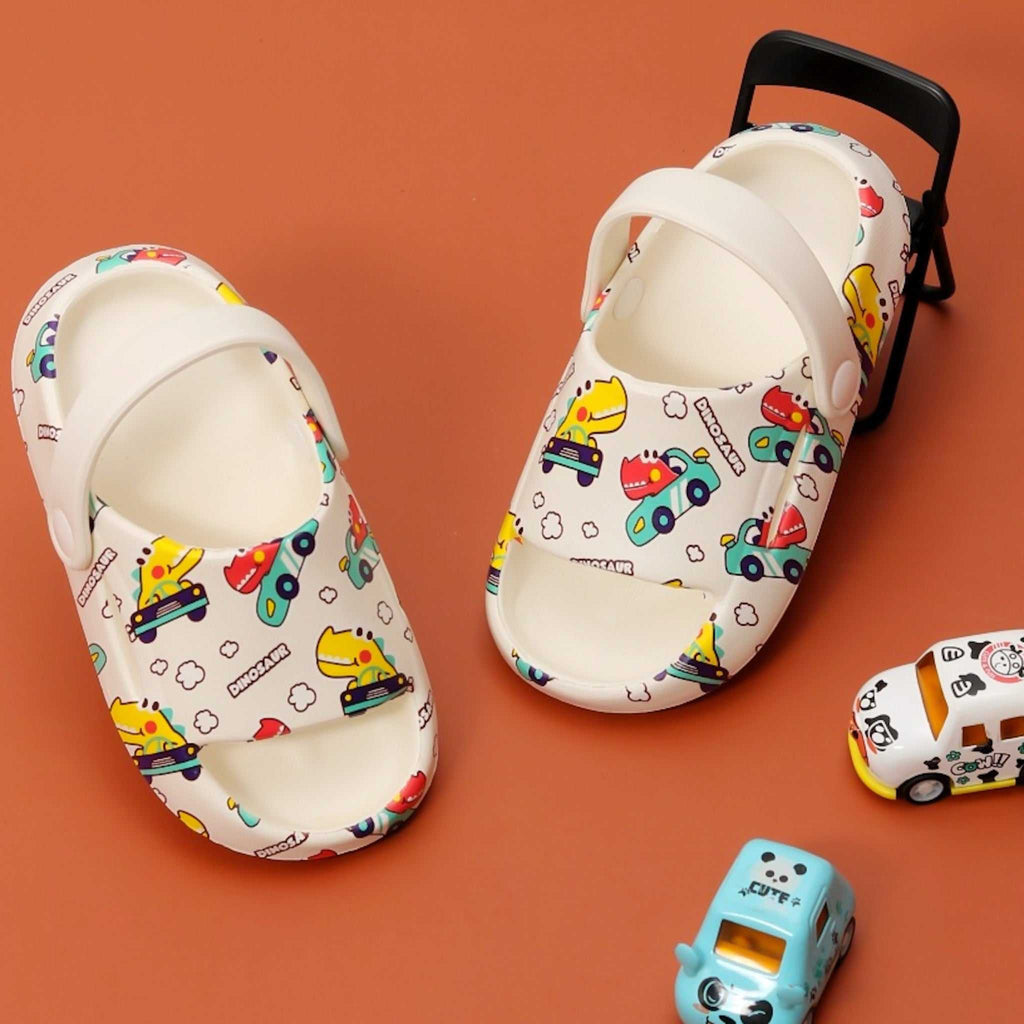 Kids' playful sandals with colorful all-over print of dinosaurs driving cars on a cream background.