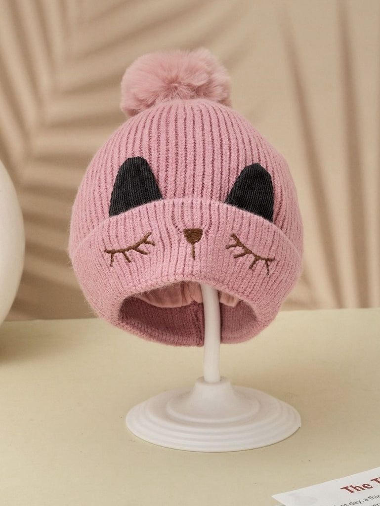 A pink winter beanie for girls with a kitten face design and a soft pom-pom.