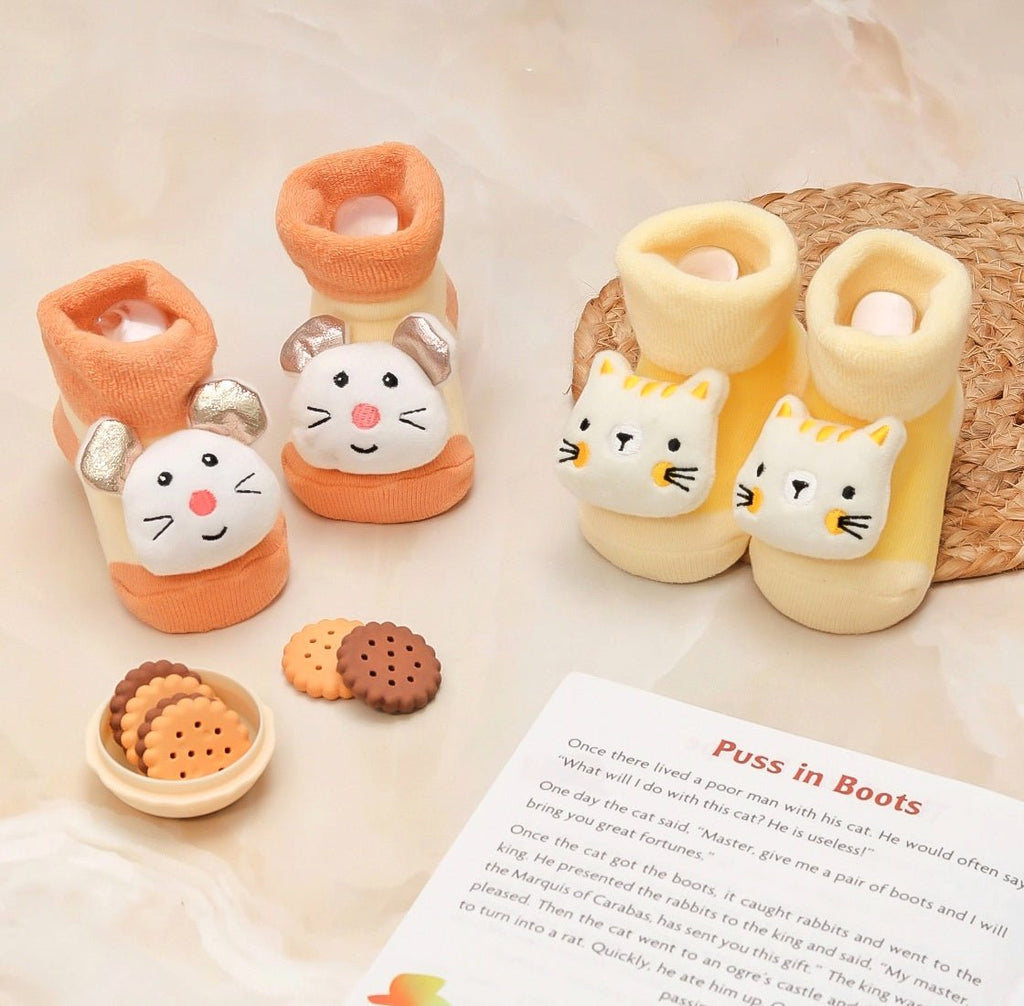 Image of Yellow Bee's kitty and mouse stuffed toy socks set arranged with storybook and cookies, ideal for baby playtime.