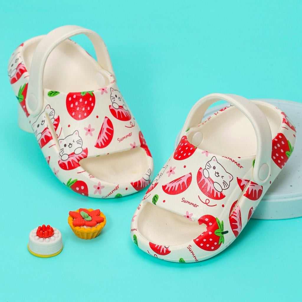 Child's white sandals with a cute strawberry and cat print on a light blue background.
