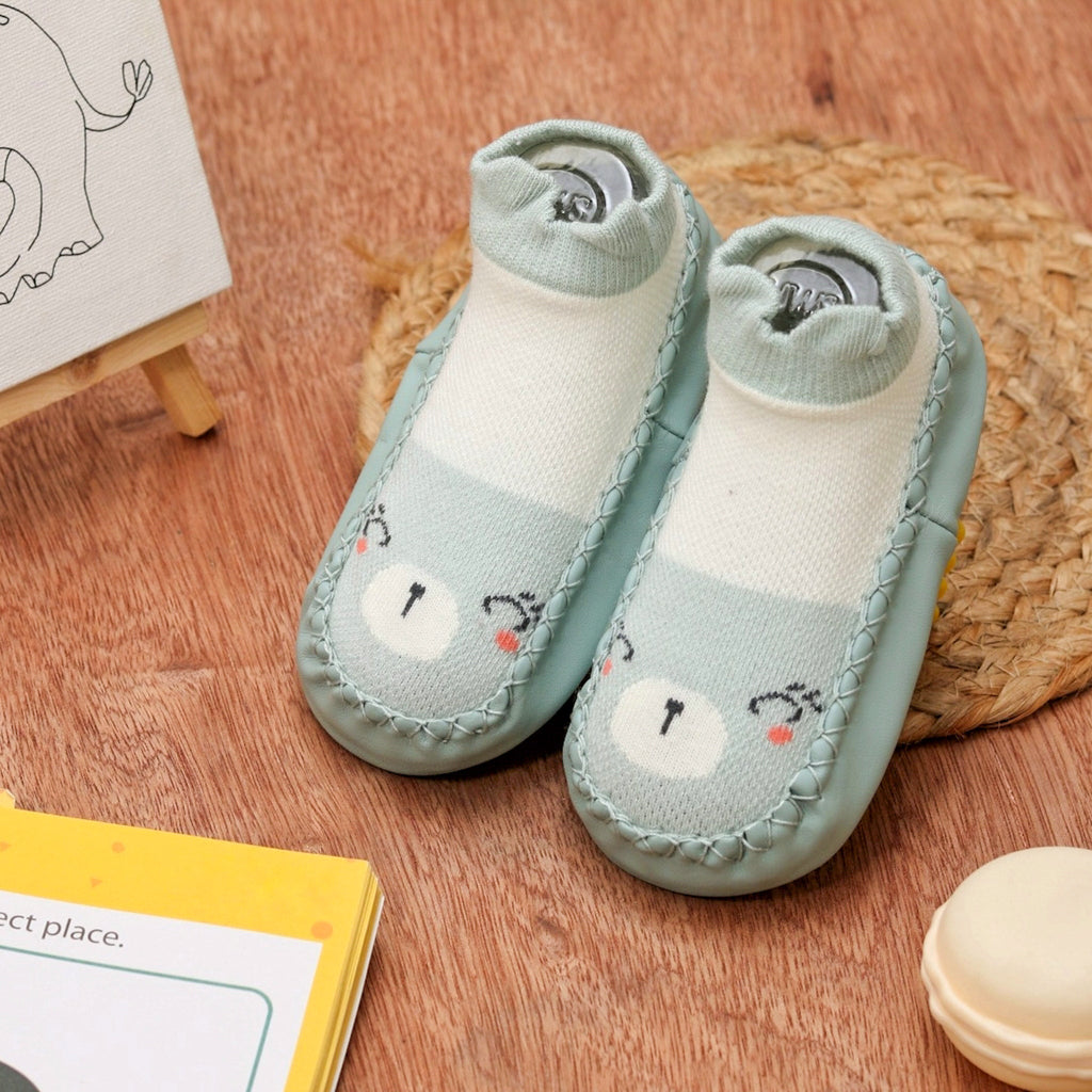 Cozy mint green kitty print leather socks for baby girls on a natural background - lifestyle shot.