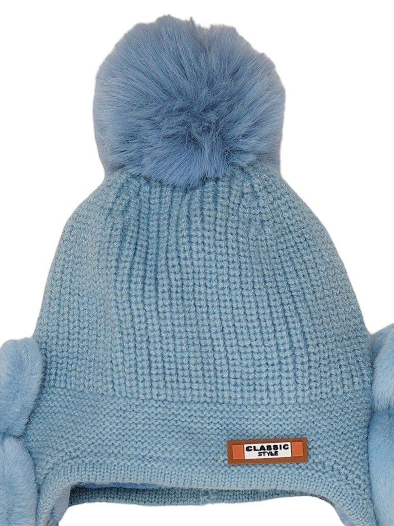 Close-up of a blue knitted children’s hat with bunny ear detail and pom pom.