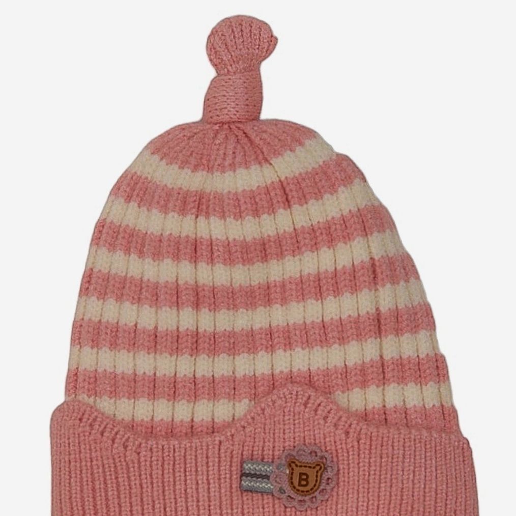 The side angle of the girl's striped winter beanie, showing the stretchable ribbed band and top knot.