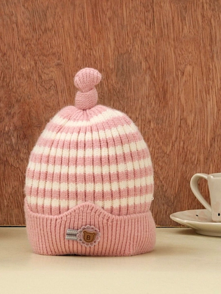 Soft light pink and white striped winter beanie for girls with a cute pompom, set against a cozy backdrop.