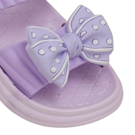 Close-up of the purple bow detail on the sandal, focusing on the dotted pattern and vibrant color.