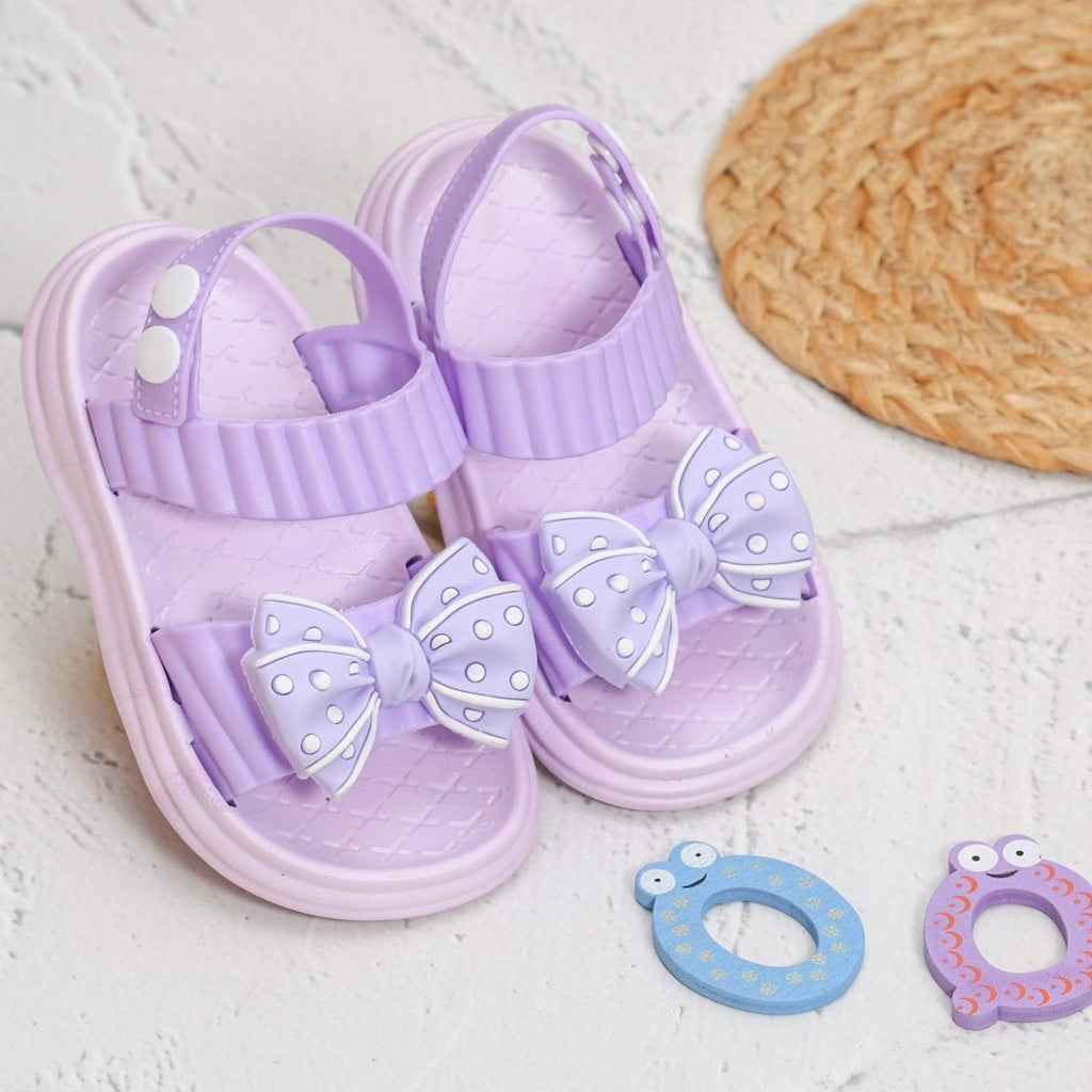 Pair of purple bow detail sandals with a charming polka dot pattern, ideal for a child's summer fashion.
