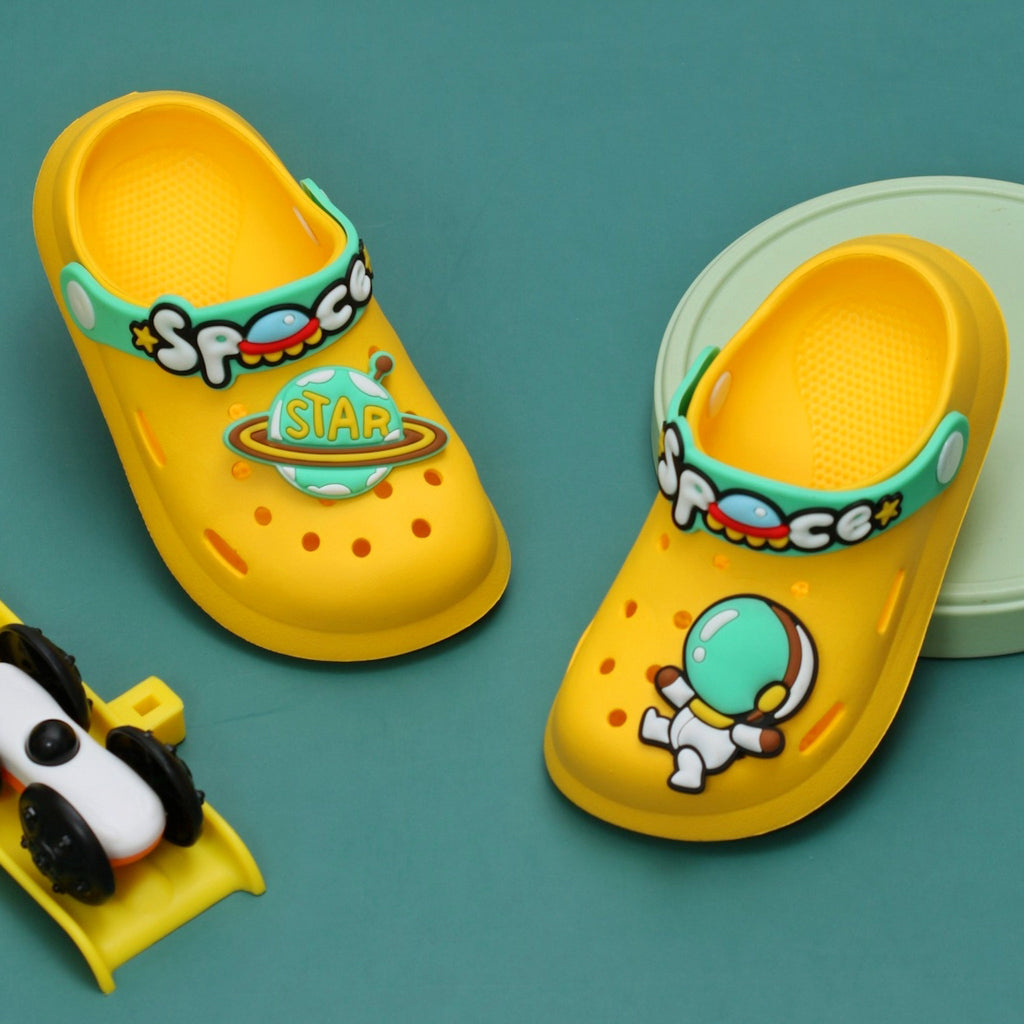 Yellow space-themed kids' clogs with astronaut and planet motifs on a teal background.