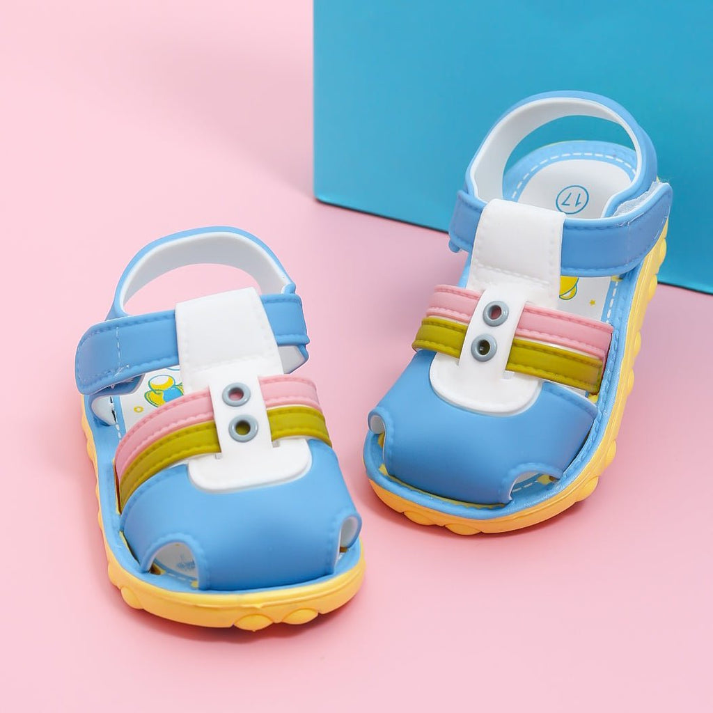 Pair of blue comfort sandals for toddlers against a pink background with a playful box.