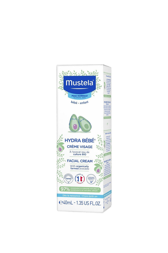 Mustela Hydra Bebe Facial Cream tube alongside an avocado, showcasing the cream's main ingredient.