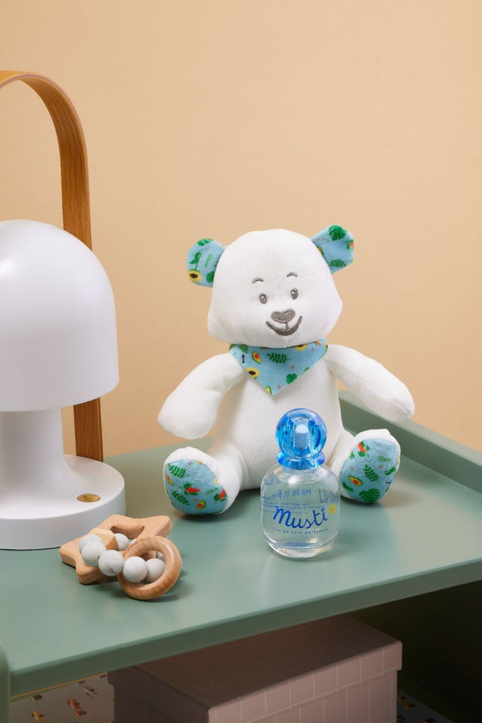 Mustela Musti Baby Fragrance presented next to a plush bear toy on a child's nightstand, embodying a soothing nursery atmosphere