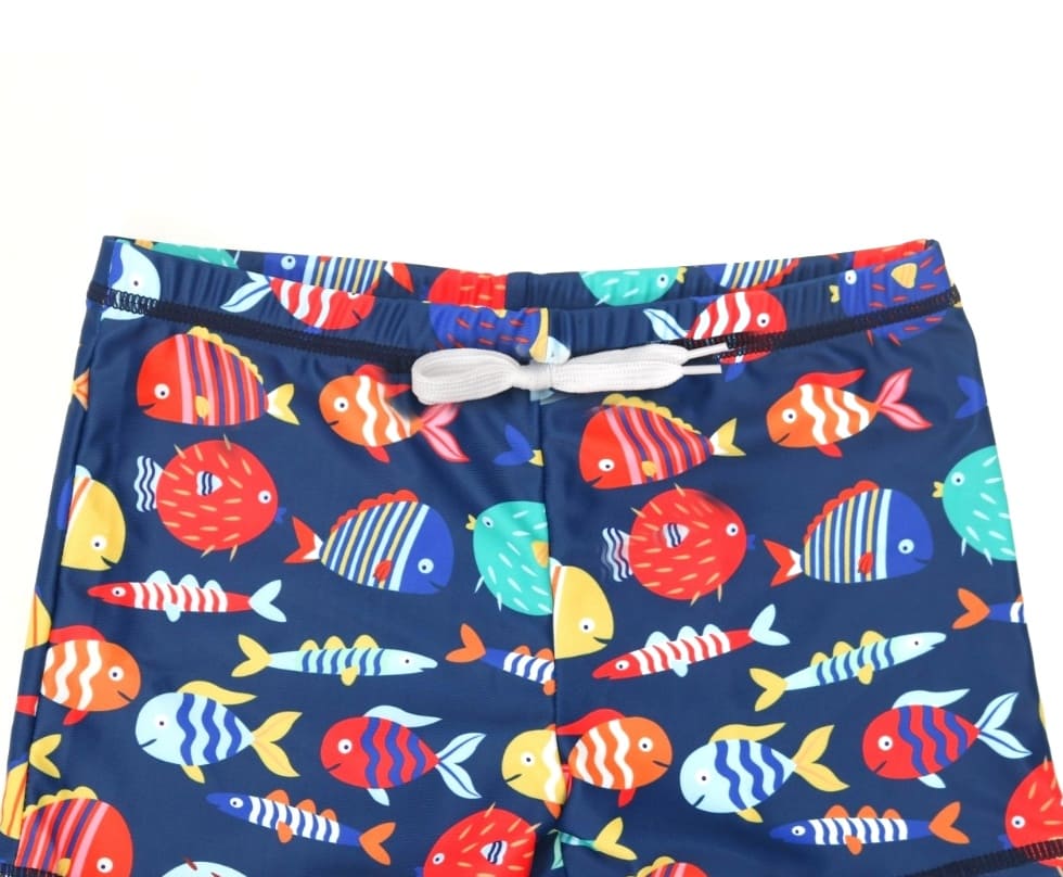 Detail of navy blue swim shorts with colorful fish print and drawstring waist