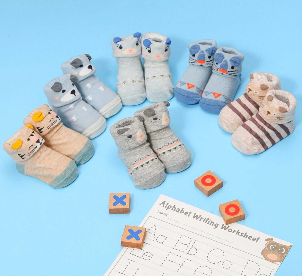 Collection of animal-themed anti-skid socks for baby boys displayed with alphabet blocks and a worksheet.