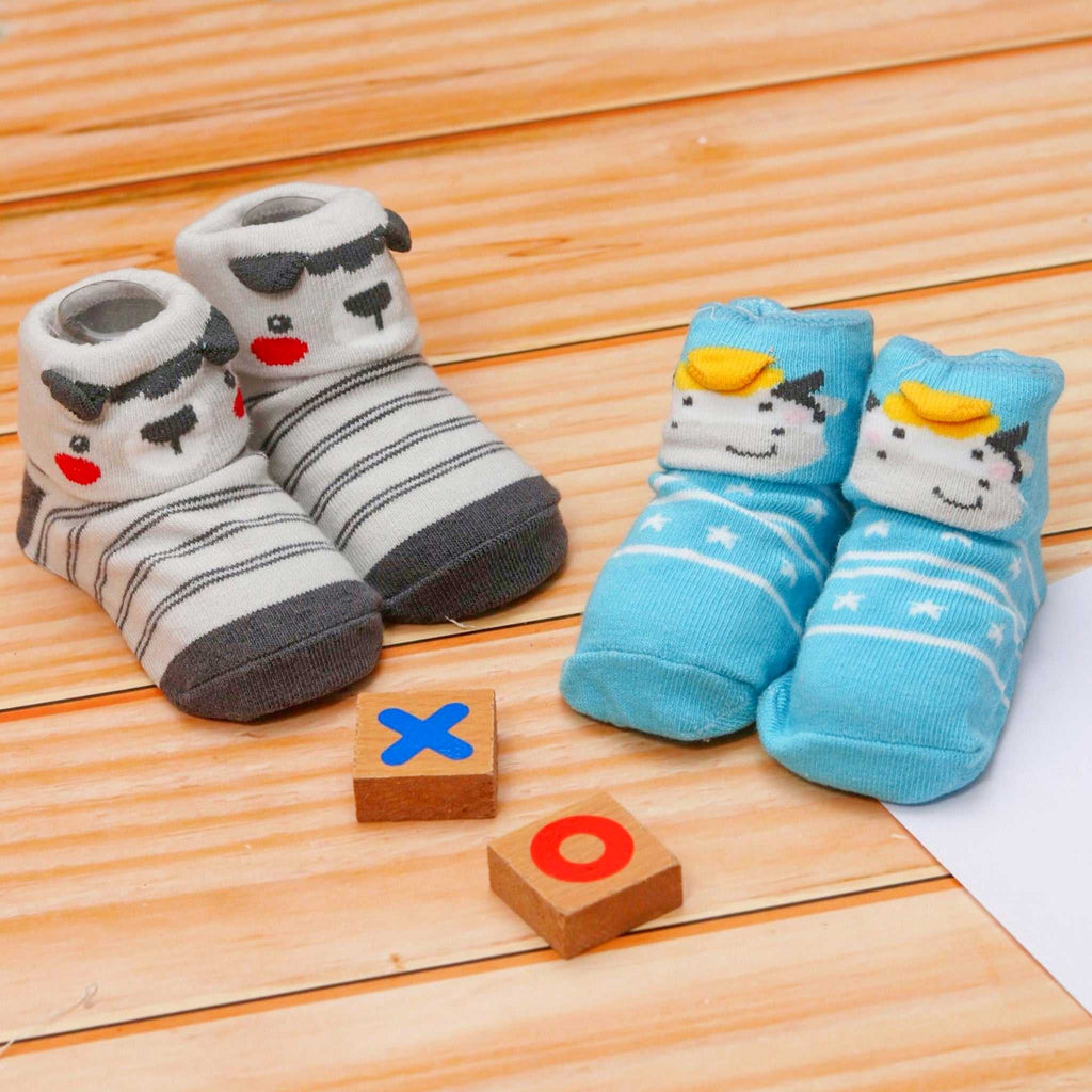 Animal-themed baby boy socks with anti-skid soles on wooden floor with toys
