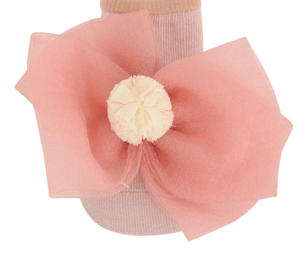 Close-up of peach-colored children's socks with a bow and contrasting flower atop.