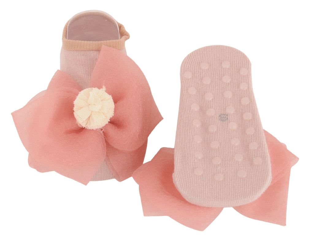 Kid's peach socks with a non-slip dotted sole and bow embellishment - angled view.
