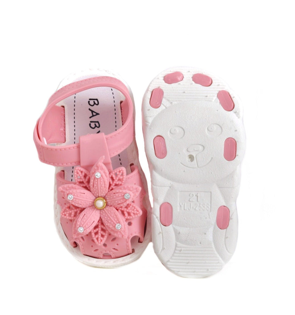 Overhead view of a pair of pink toddler sandals with flower details and anti-slip soles.