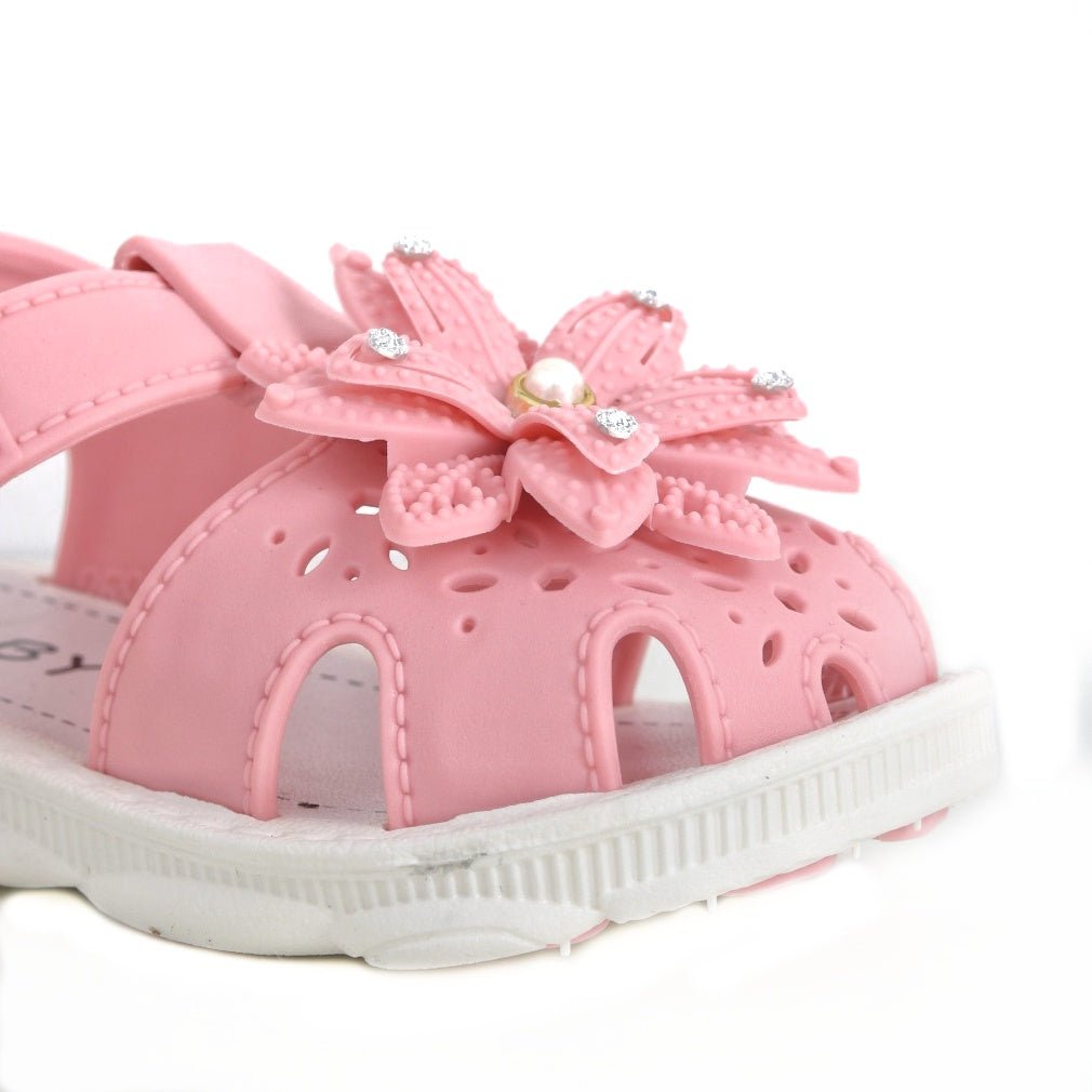 Close-up of the floral detail on a child's pink sandal with sparkly accents.