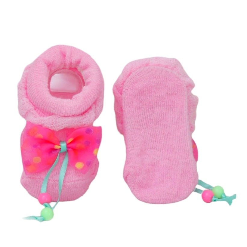 Baby girl socks with a pink bow detail, displaying the sole with anti-slip dots.