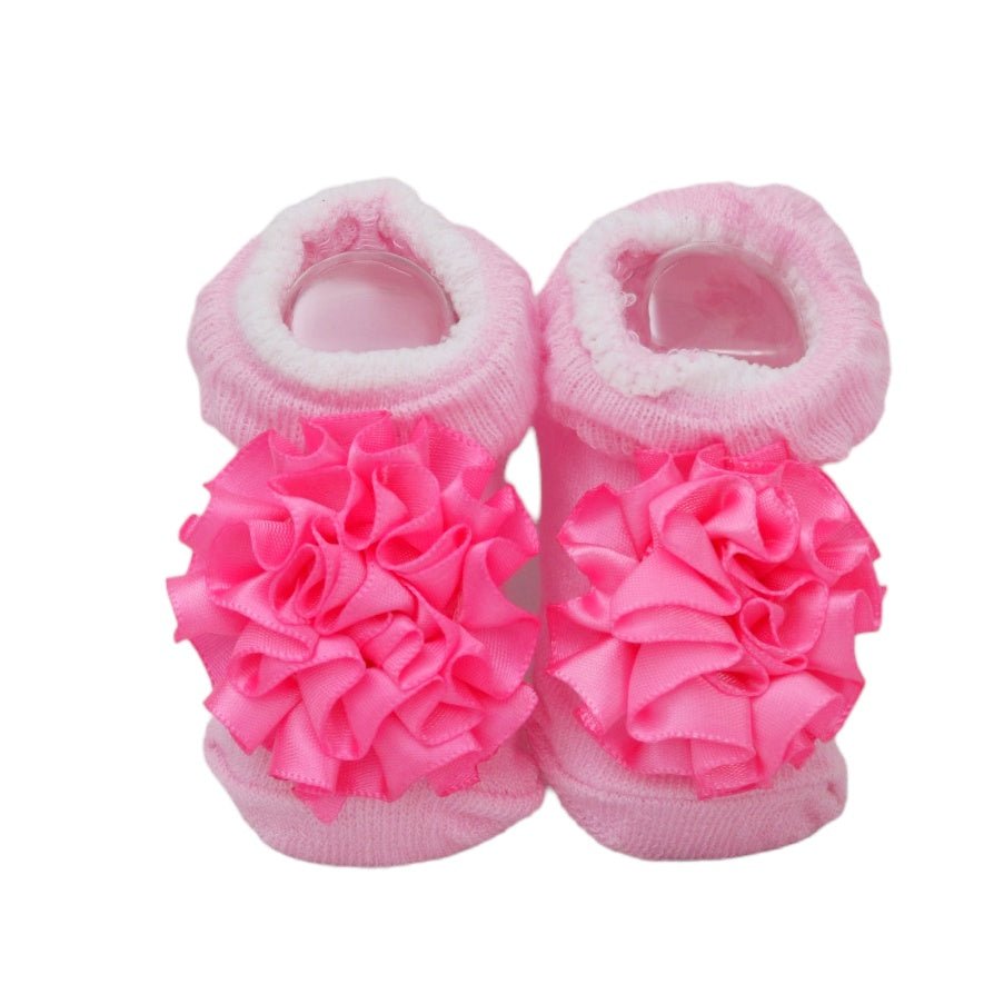 Soft pink baby socks adorned with large frilly flowers for a touch of elegance.