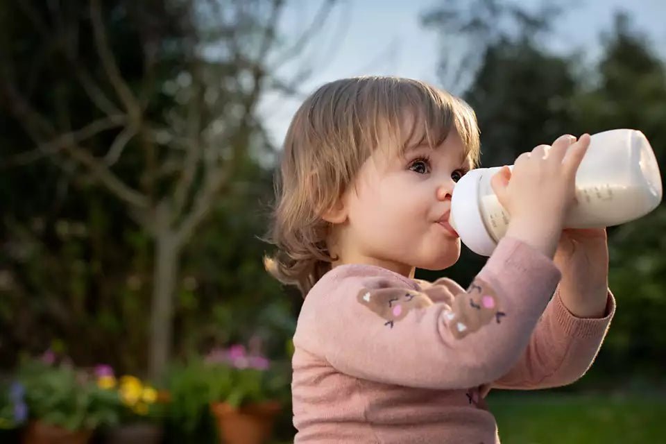 Child happily drinking from Philips Avent SCY906/01 Natural Feeding Bottle in a garden setting
