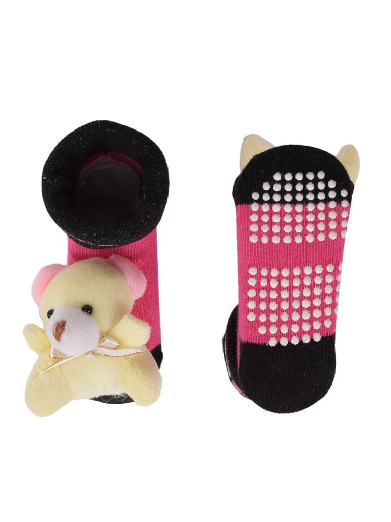 Top view of pink infant socks with teddy bear stuffed toy attached to the front