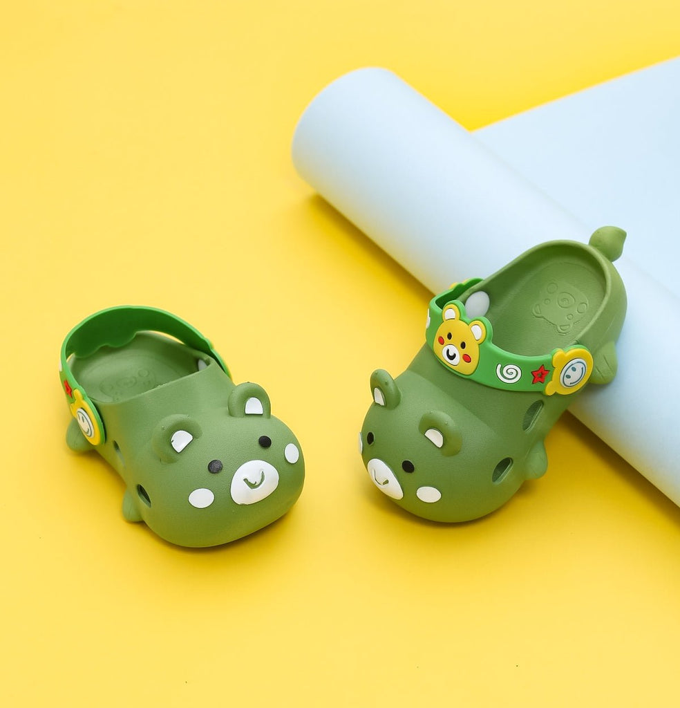 Pair of kids' bear pattern clogs in green with decorative animal face charms on a yellow background