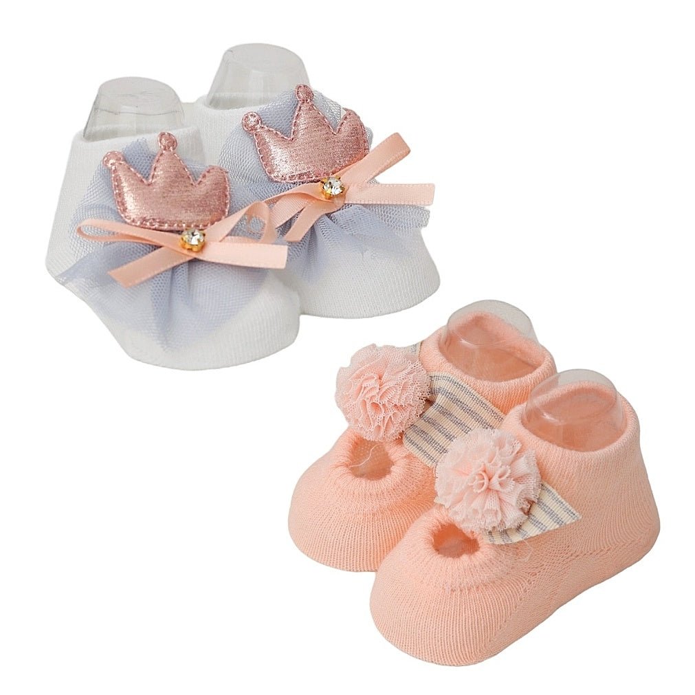 Set of peachy pink and white baby socks with pom-poms and crown embellishments