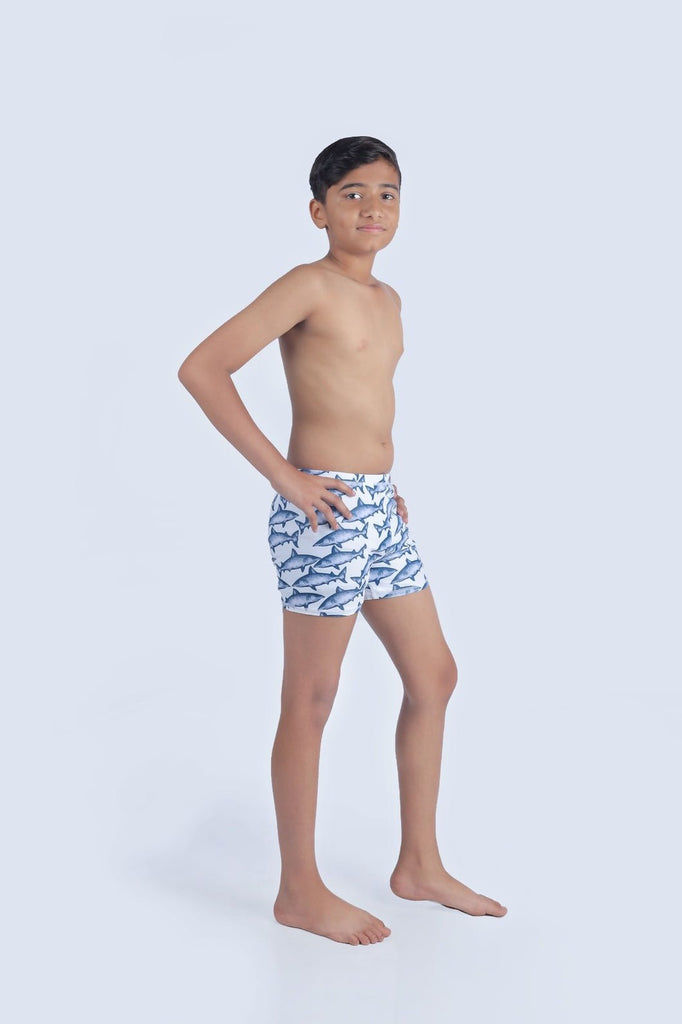 Side view of boy in shark print swim shorts, poised for summer fun