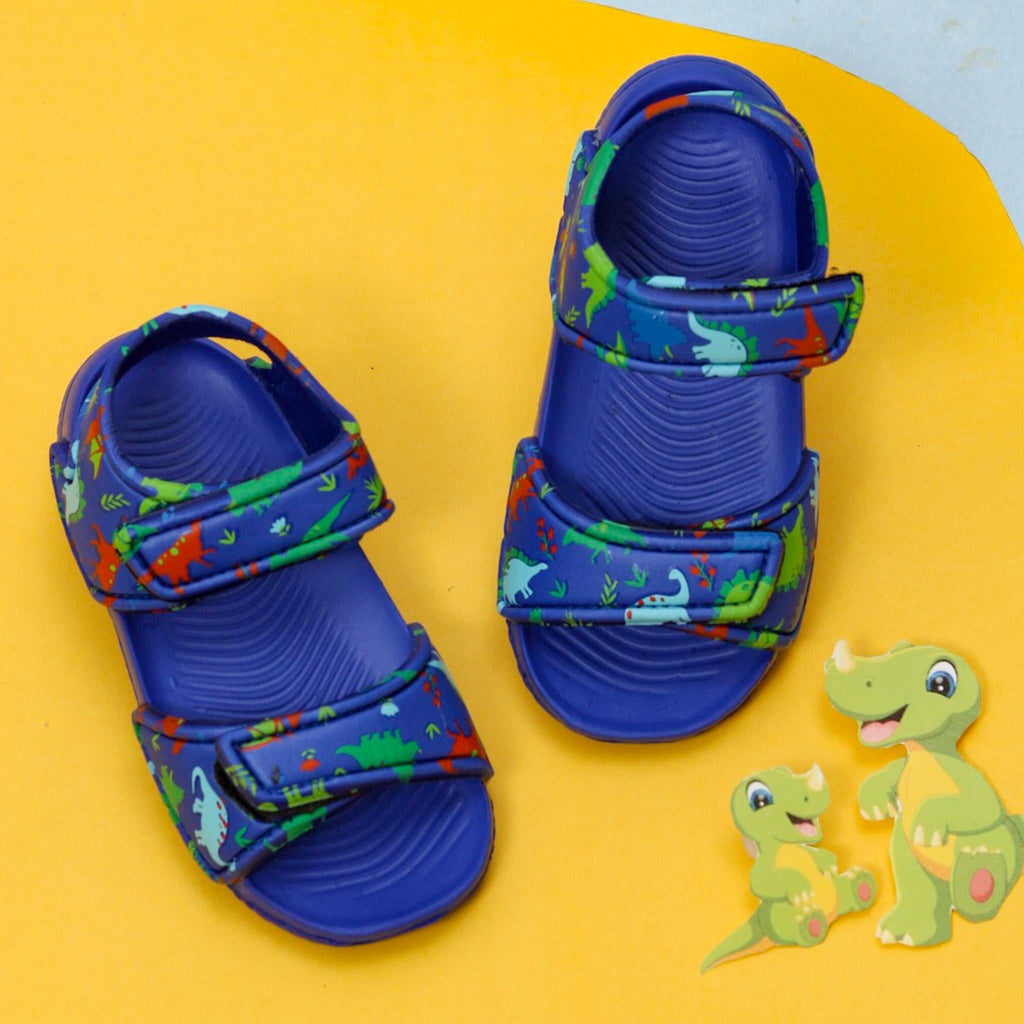 Kids' blue sandals with a vibrant all-over dinosaur print on a contrasting yellow background.