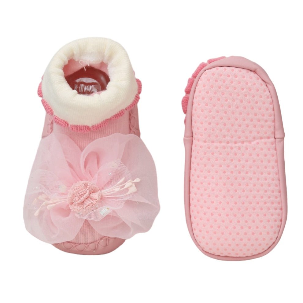 Side and sole view of baby girl's pink leather socks with non-slip dots and flower decoration