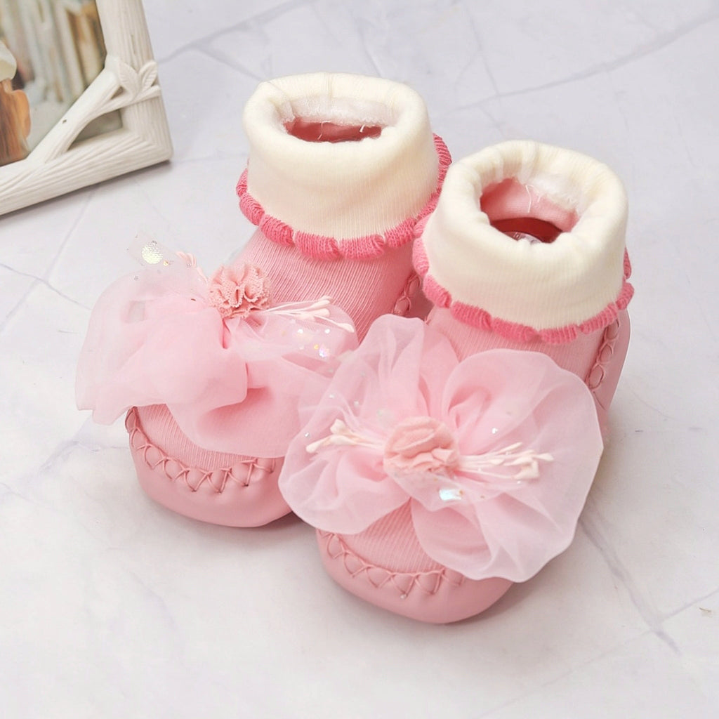 Baby girl's pink leather socks adorned with a large 3D flower applique and soft ribbed cuffs