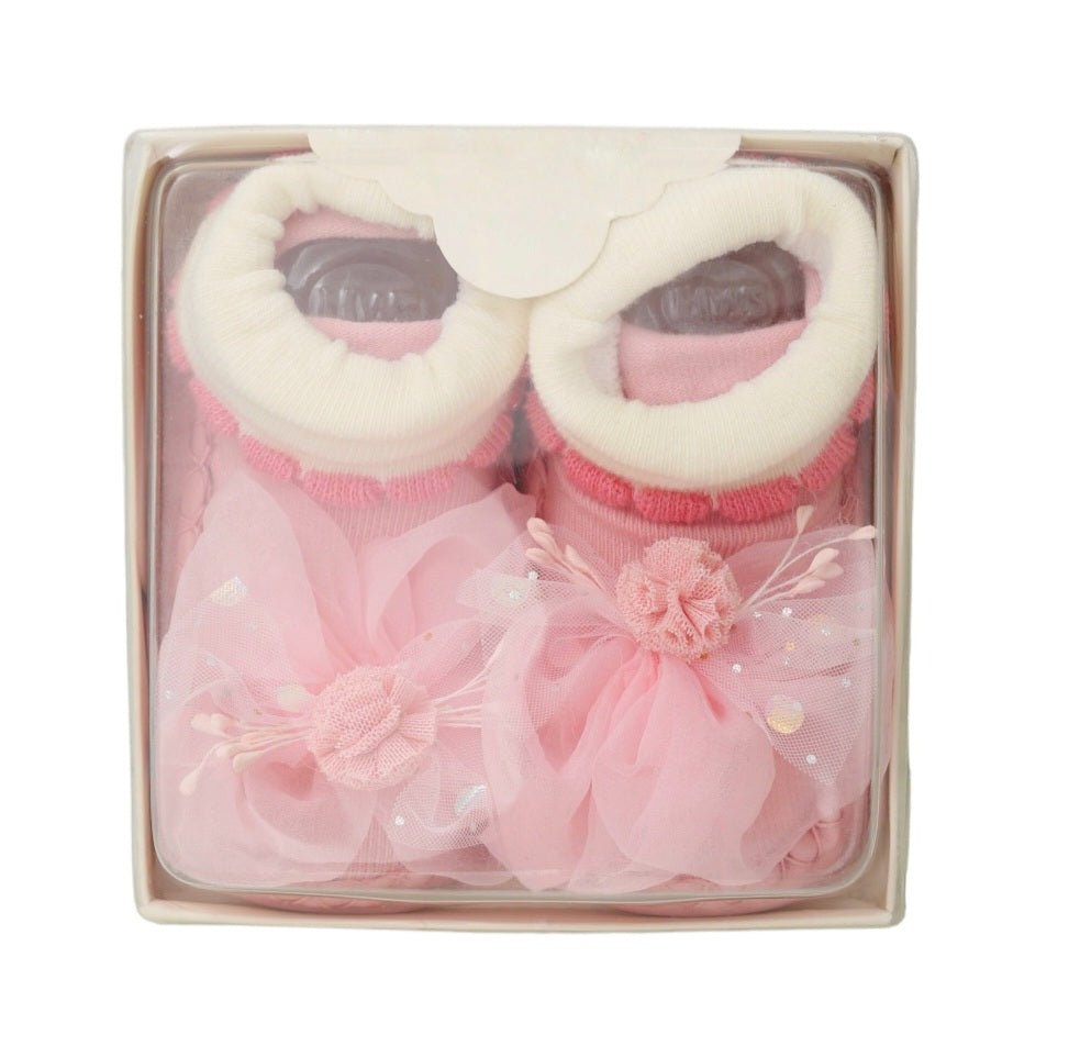 Pair of baby girl's leather socks with 3D flower detail, packaged in a clear gift box